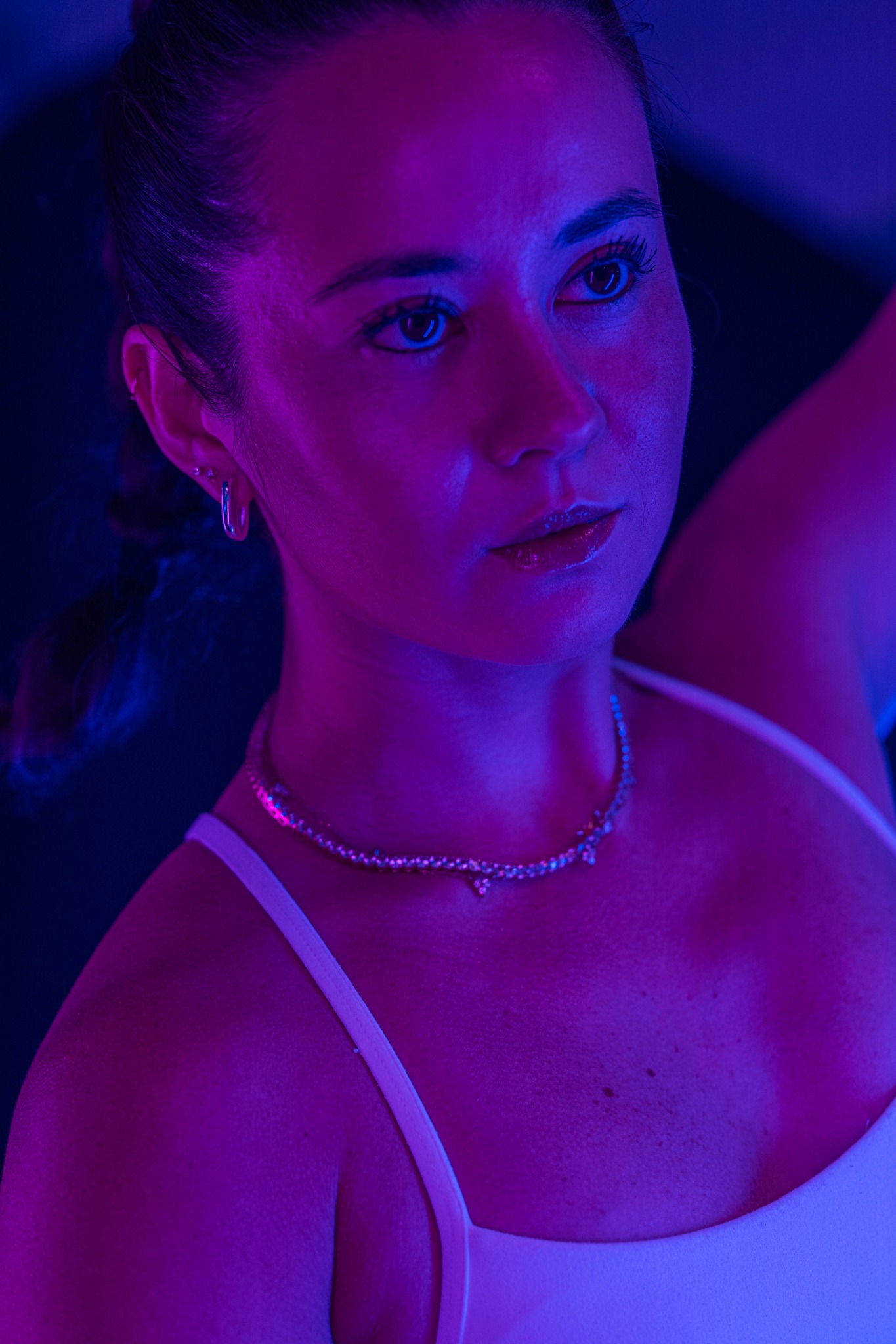 Portrait of an athlete looking toward the camera under purple and blue studio lighting.