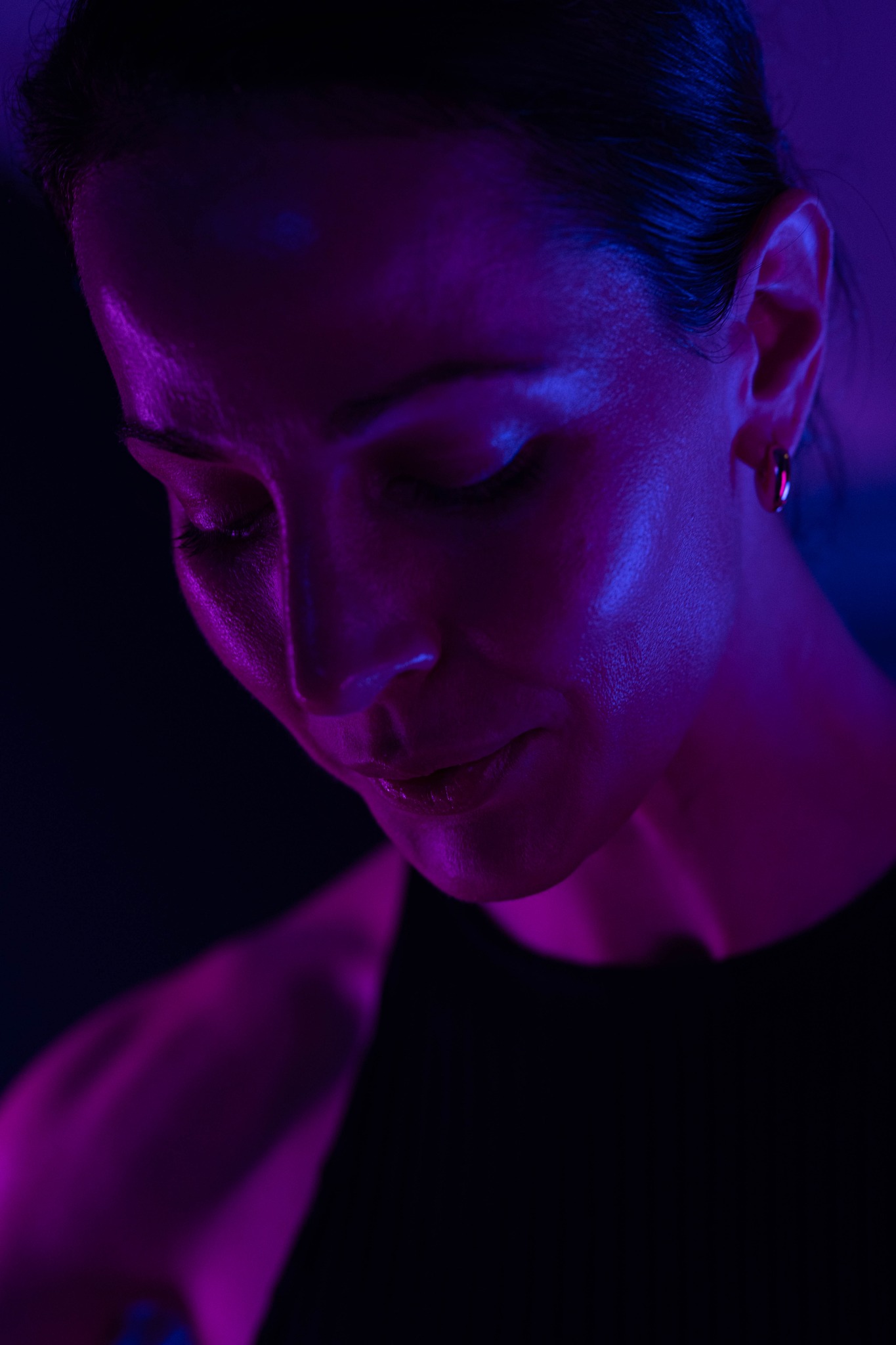 Athlete looking down in vivid purple and blue studio lighting.